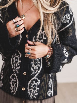 Person wearing a patterned cardigan with jewelry