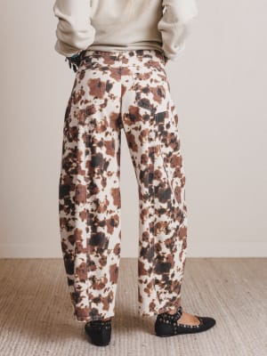 Person wearing floral-patterned pants and a light-colored top on a neutral background