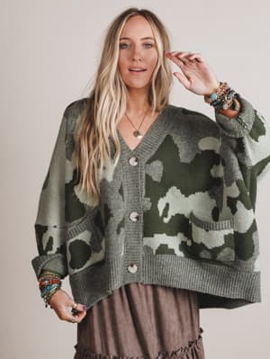 Woman wearing a camouflage cardigan against a plain background