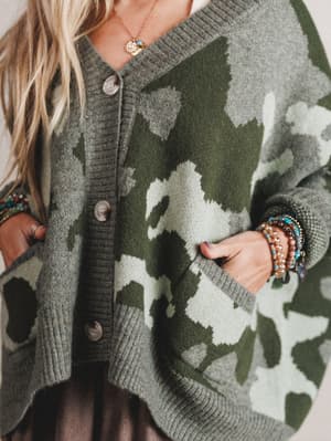 Person wearing a camouflage-patterned cardigan with buttons.