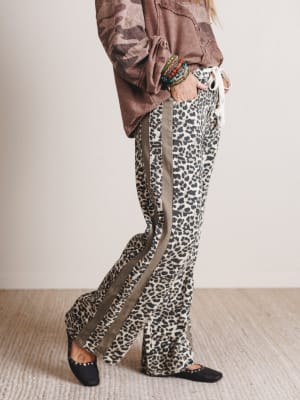 Person wearing leopard print pants with a neutral background