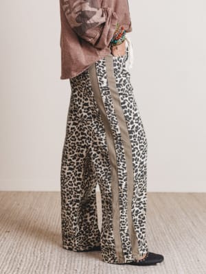 Person wearing leopard print pants with a plain background
