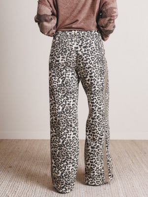 Person wearing leopard print pants with a plain background