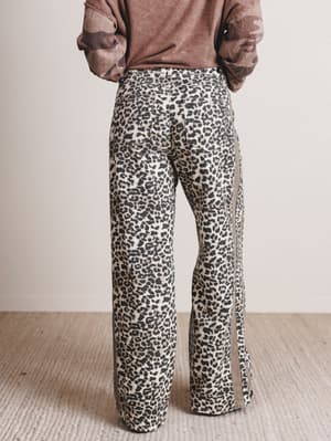 Person wearing leopard print pants with a plain background