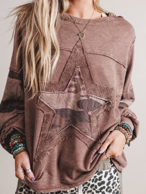 Brown sweatshirt with star design worn by a person, with a neutral background