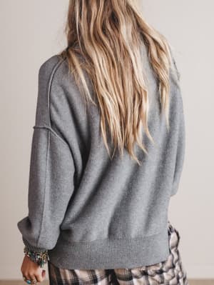 Person wearing a gray sweater with a neutral background