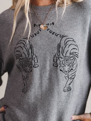 Gray sweater with black tiger designs worn by a person