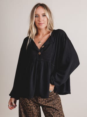 Woman wearing a black blouse and leopard print pants against a plain background