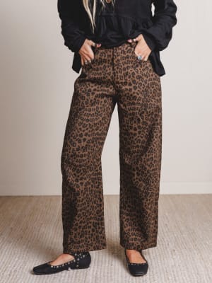 Person wearing leopard print pants and black top on a neutral background