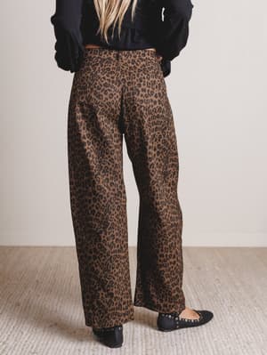 Person wearing leopard print pants on a neutral background