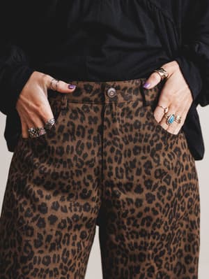 Person wearing leopard print pants with a plain background