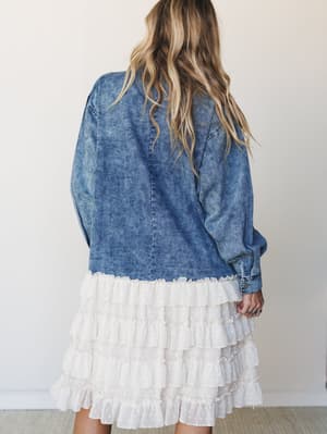 Shot from behind, this washed indigo denim jacket layers effortlessly over a cream tiered ruffle skirt — the kind of outfit that looks like it came together accidentally but absolutely didn't.