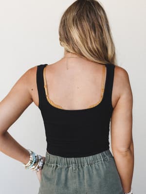 Shot from the back, this look pairs a black textured tank with sage green relaxed bottoms and a stack of beaded bracelets — effortless and a little sun-kissed, like a good Saturday with nowhere to be.