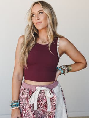 A relaxed boho look built around a deep burgundy ribbed crop tank, paired with a paisley drawstring skirt and layered with stacked turquoise and beaded bracelets — the kind of outfit that looks effortless but is clearly very much on purpose.