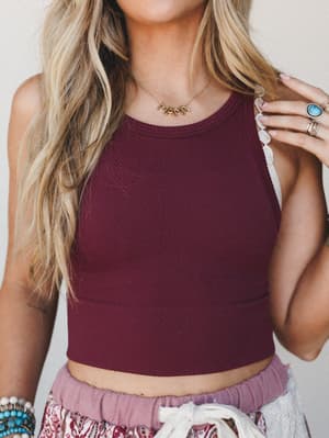 A cropped burgundy tank with a subtle chevron texture is styled with a flowy printed bottom and layered boho jewelry — the kind of effortless mix that looks thrown together but definitely wasn't.