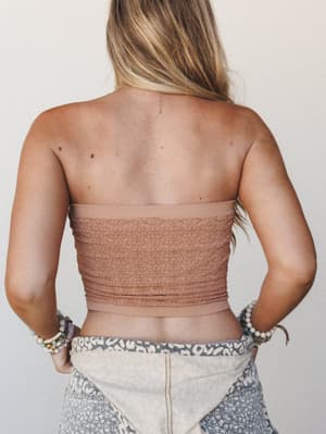 A back-facing shot showing a lace tube top in warm mocha layered over patchwork bottoms — the kind of effortless warm-weather outfit that looks like it came together on purpose.