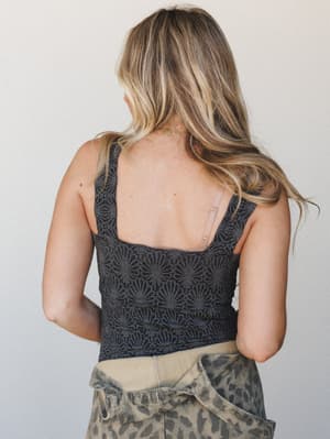 A back-facing shot showing a textured black tank top with an allover floral burnout pattern paired with olive leopard-print denim, giving off that effortlessly put-together energy — the kind of outfit that looks like you tried just the right amount.