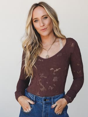 A lace bodysuit in deep burgundy layered over a neutral cami, tucked into high-waist denim — the kind of outfit that looks effortless but was absolutely thought about.