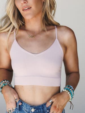 A soft pearl blush bralette styled with vintage denim and stacked turquoise bracelets — the kind of effortless, jewelry-heavy look that feels equally at home on a beach boardwalk or a lazy Sunday morning.