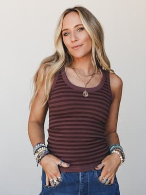 A ribbed striped tank in deep plum tones styled with stacked beaded bracelets, layered gold necklaces, and denim — the kind of effortless everyday look that does all the talking.