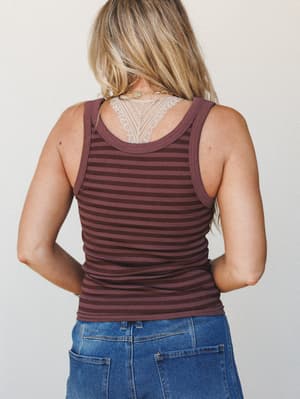 Shot from behind, a striped ribbed tank in deep mauve and chocolate tones is paired with medium-wash denim — the lace back detail peeking out at the neckline is the quiet little detail that makes the whole thing.