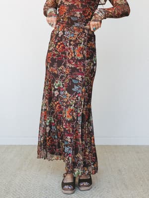 A rich chocolate floral mesh maxi skirt styled with a matching long-sleeve floral top, silver and turquoise rings, and platform sandals — the kind of head-to-toe autumn print moment that feels personal, not precious.