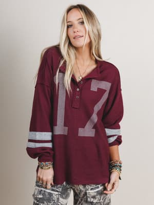 Woman wearing a maroon long-sleeve shirt with large numbers on a plain background