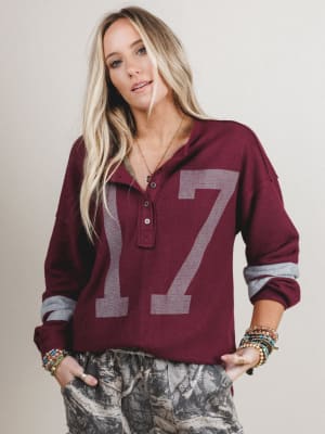 Woman wearing a maroon long-sleeve shirt with the number 17 on a plain background
