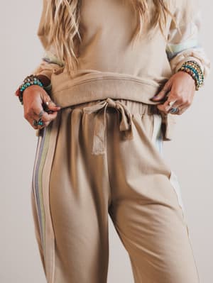 Person wearing a beige outfit with striped sleeves against a neutral background