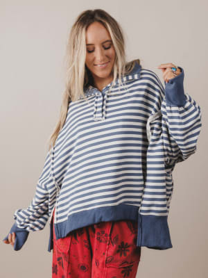 Woman wearing a blue and white striped hoodie with red pants against a plain background