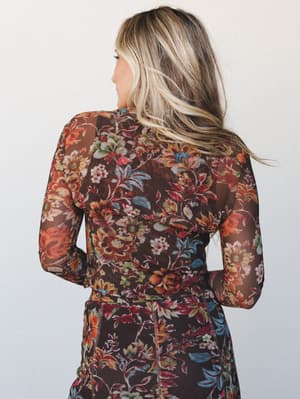 A back-facing shot of a sheer chocolate floral top with long sleeves, layered over a matching floral skirt or pant — the warm autumn blooms and semi-sheer mesh fabric give it that romantic, lived-in feel.
