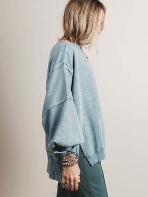 Person wearing a light blue oversized sweater with a neutral background