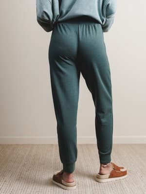 Person wearing teal jogger pants and a light blue sweatshirt on a neutral background