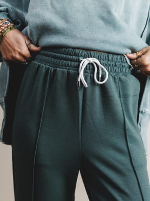 Person wearing teal sweatpants with a white drawstring on a neutral background