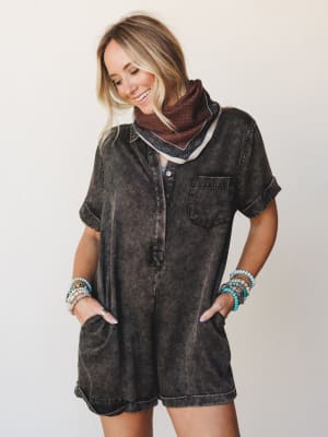 A mineral-washed black romper styled with a paisley bandana scarf and stacked turquoise bracelets — the kind of effortless outfit that looks like you tried just enough.