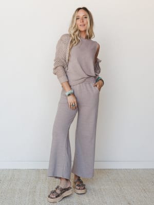 A matching knit set in soft ash mocha — sleeveless top and wide-leg pants layered under an open-weave crochet cardigan — styled with stacked turquoise bracelets and leopard platform sandals for an effortlessly put-together everyday look.