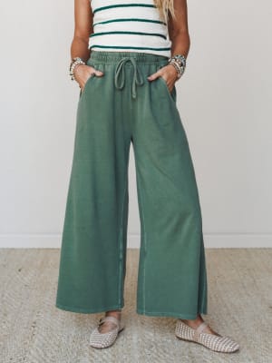 Wide-leg drawstring pants in a washed dark green styled with a striped sweater top and woven flats — the kind of outfit that looks intentional but feels like your most comfortable day.