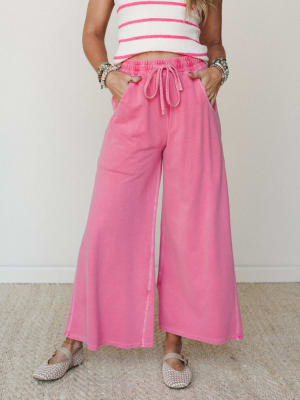 Wide-leg drawstring pants in a faded bubblegum pink styled with a cropped stripe top and woven flats — easy, playful, and the kind of outfit that looks effortless but totally isn't.