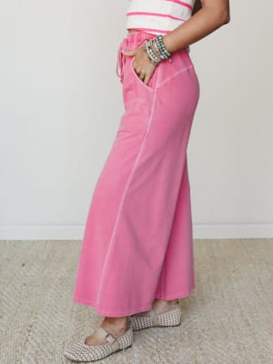 A side-profile shot of a washed pink maxi skirt styled with a cropped striped knit top and woven Mary Jane flats — playful, relaxed, and stacked with beaded bracelets for that effortless personal-style energy.