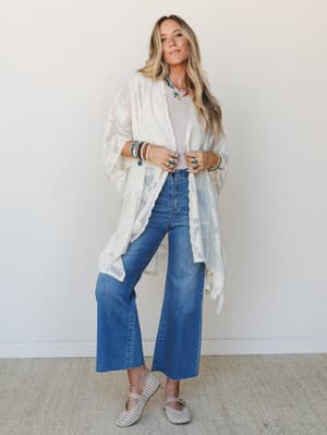 A breezy, fully-accessorized look built around a cream lace kimono layered over a soft neutral tee and cropped wide-leg jeans — the kind of outfit that looks effortless but very much on purpose.