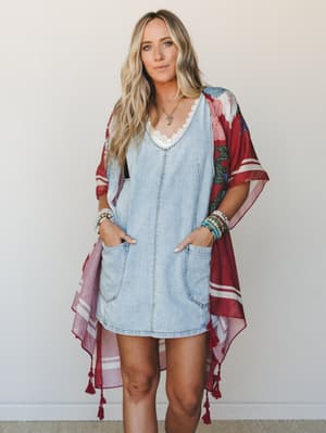 A light-wash denim mini dress layered under a flowy burgundy floral kimono with tassel hem — the kind of outfit that feels effortless but clearly wasn't an accident.
