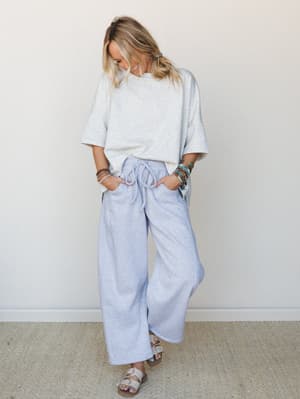 A relaxed, effortless two-piece set in soft heather gray tones — oversized tee tucked loosely into wide-leg drawstring pants, styled with sandals and a stack of boho bracelets that do all the personality-talking.