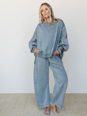 A relaxed, matching two-piece set in washed slate blue — oversized sweatshirt and wide-leg pants styled with stacked beaded bracelets and a gold necklace, giving off that effortlessly put-together, cozy-day energy.