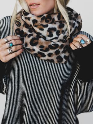 Person wearing a leopard print scarf with a striped outfit on a white background