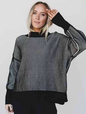 Woman wearing a black and white striped sweater against a plain background