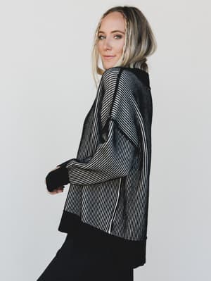Woman wearing a black and white striped jacket against a plain background