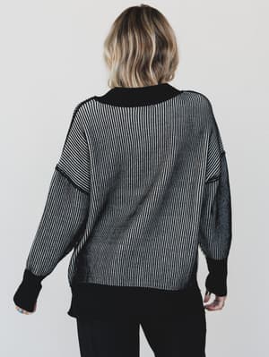 Person wearing a black and white patterned sweater on a plain background