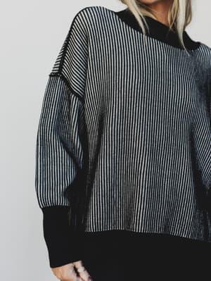 Person wearing a black and white striped sweater against a plain background