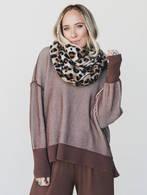 Woman wearing a brown sweater and leopard print scarf against a white background