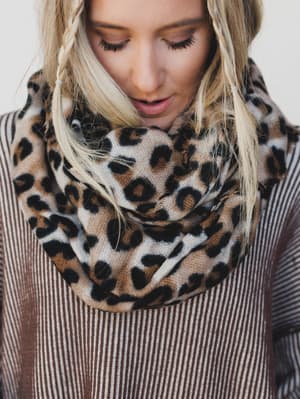 Person wearing a leopard print scarf with a neutral background